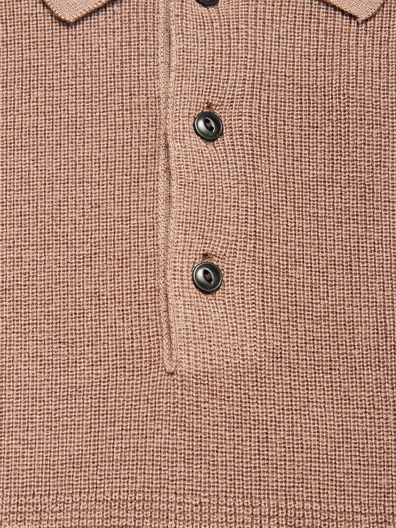 Close-up of the Blue de Gênes Porto Polo Knit - Fungi, a textured light brown wool polo shirt featuring three black buttons and part of the collar, reflecting casual elegance.