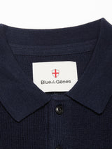 Close-up of the Porto Polo Knit - Navy by Blue de Gênes, featuring textured fabric and a label with a red cross emblem—ideal for casual elegance.