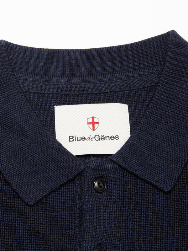 Close-up of the Porto Polo Knit - Navy by Blue de Gênes, featuring textured fabric and a label with a red cross emblem—ideal for casual elegance.
