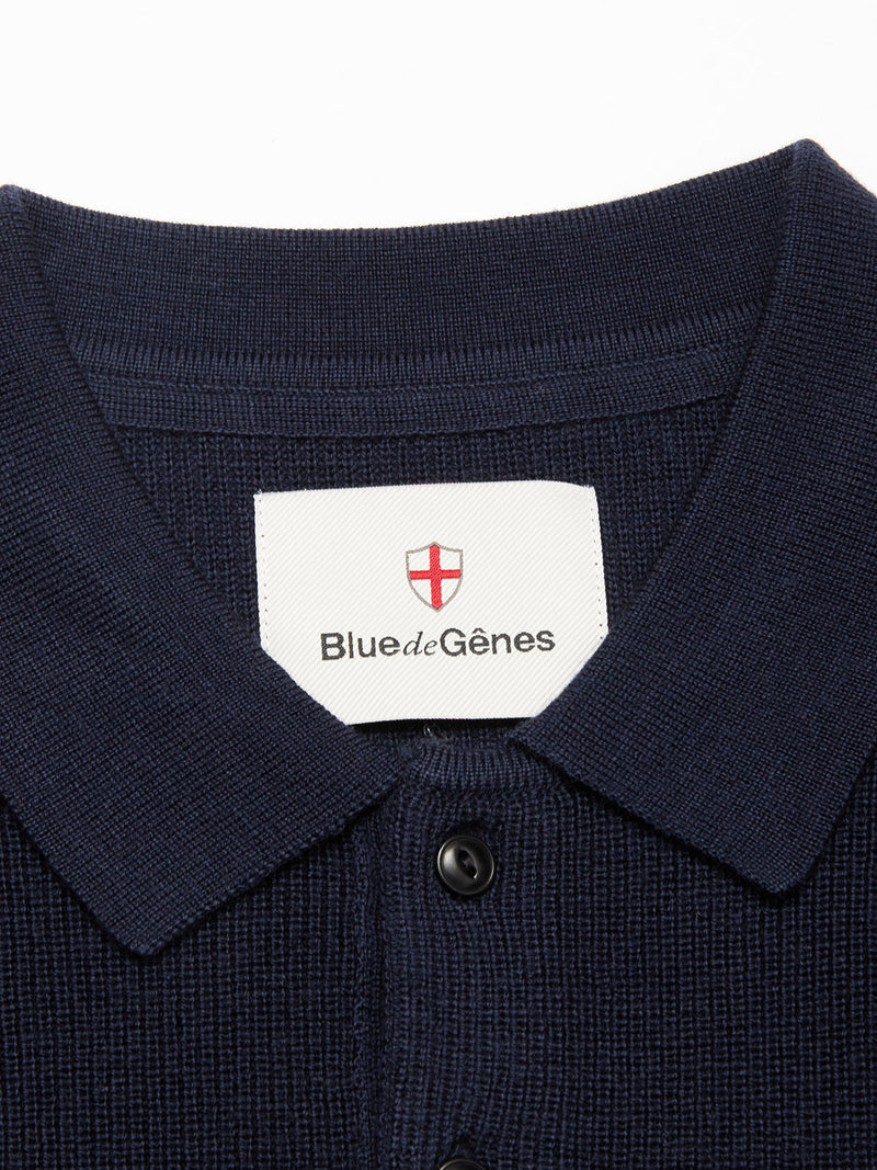 Close-up of the Porto Polo Knit - Navy by Blue de Gênes, featuring textured fabric and a label with a red cross emblem—ideal for casual elegance.