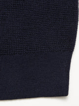 Close-up of the Blue de Gênes Porto Polo Knit in navy, featuring a tighter ribbed hem and fine wool knit texture, showcasing the casual elegance of this polo shirt against a light background.