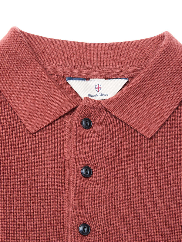 Close-up of the Porto Polo Knit in Henna by Blue de Gênes, featuring a rust hue, collar, three black buttons, and an inner label with brand name and crest—showcasing refined men’s luxury knitwear.