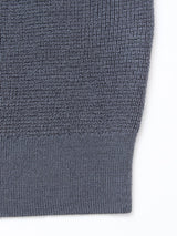 Close-up of the Porto Polo Knit - Dark Slate by Blue de Gênes, highlighting its ribbed hem and textured knit pattern against a white background.