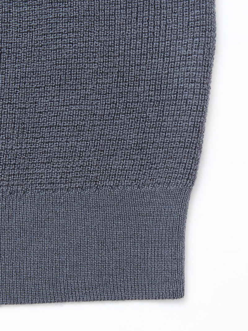 Close-up of the Porto Polo Knit - Dark Slate by Blue de Gênes, highlighting its ribbed hem and textured knit pattern against a white background.