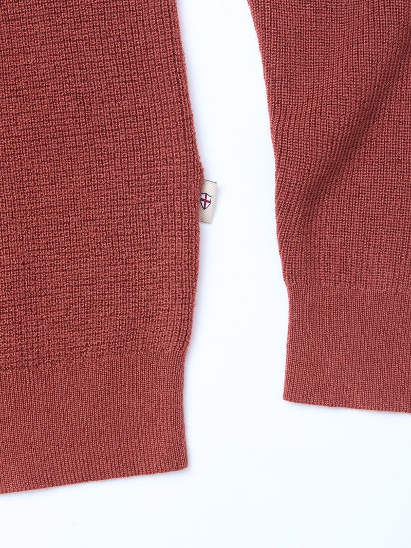The Porto Polo Knit - Henna by Blue de Gênes is a red sweater with a white tag, ideal for refined leisurewear.