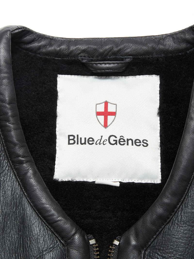 Close-up of the Saga Shearling Gilet - Scarab’s collar and inner lining, featuring a white label with a red shield and cross, Blue de Gênes branding, and traces of German Merino sheepskin for added luxury.