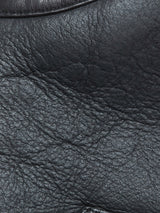 Close-up of black German Merino sheepskin leather on the Blue de Gênes Saga Shearling Gilet - Scarab, highlighting natural wrinkles, creases, glossy finish, and grain patterns—ideal for its reversible shearling design.