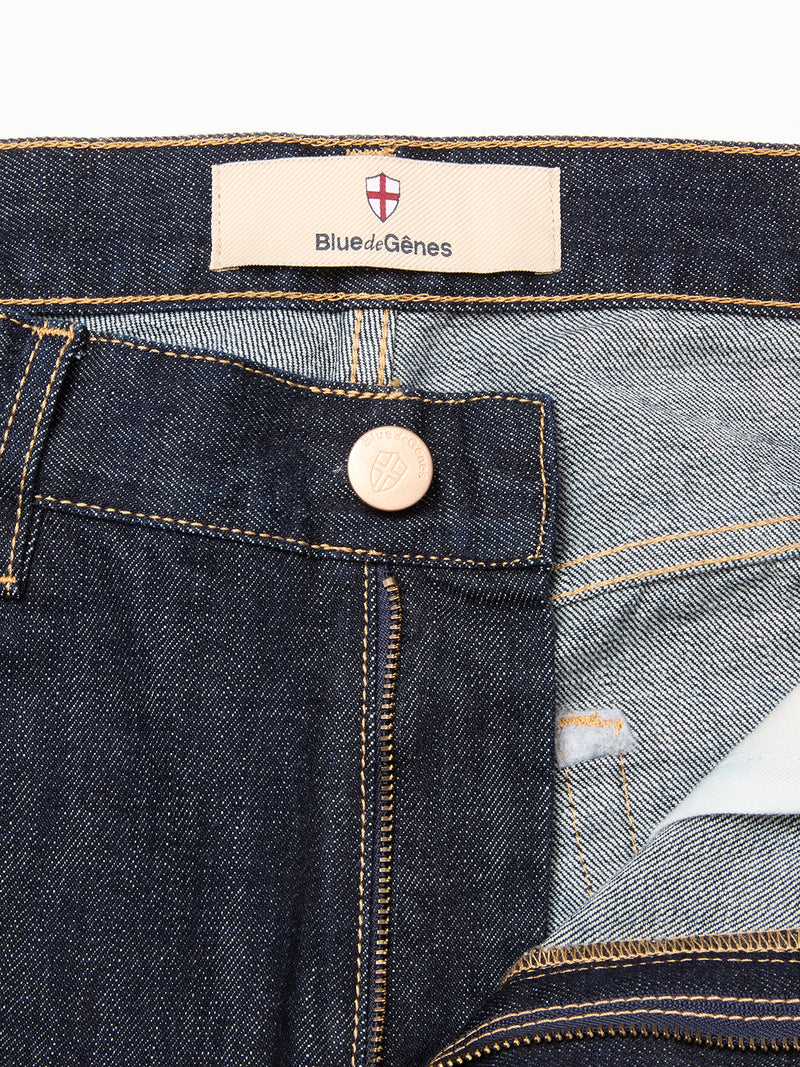 Close-up of Blue de Gênes Marco Rinse Jeans - Rinse Wash in dark blue 100% cotton denim, featuring a branded waistband label, crest metal button, front pocket, and yellow stitching inside and out.