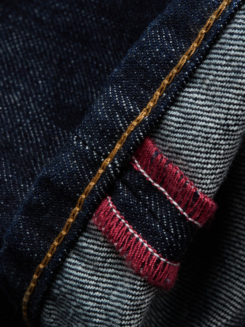 Close-up of the cuff on Blue de Gênes Marco Rinse Jeans – Rinse Wash, highlighting yellow stitching and red and white selvedge edges inside the relaxed fit dark blue denim.