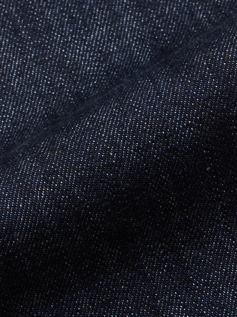 Close-up of Blue de Gênes Marco Rinse Jeans dark blue 100% cotton denim with visible diagonal weave and fine white specks, highlighting texture and slight fold—ideal for relaxed fit or used styles.