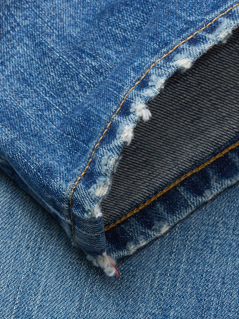 Close-up of the frayed hem on a Blue de Gênes Marco Used Jeans leg, with orange stitching and visible white threads. Made from 100% cotton denim in classic indigo wash with textured details.