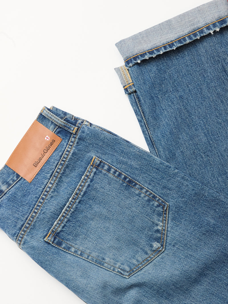Two pairs of Blue de Gênes Marco Used Jeans - Used are laid flat; one displays the back pocket with a brown leather patch, the other is folded to reveal the cuff and 100% cotton denim texture.