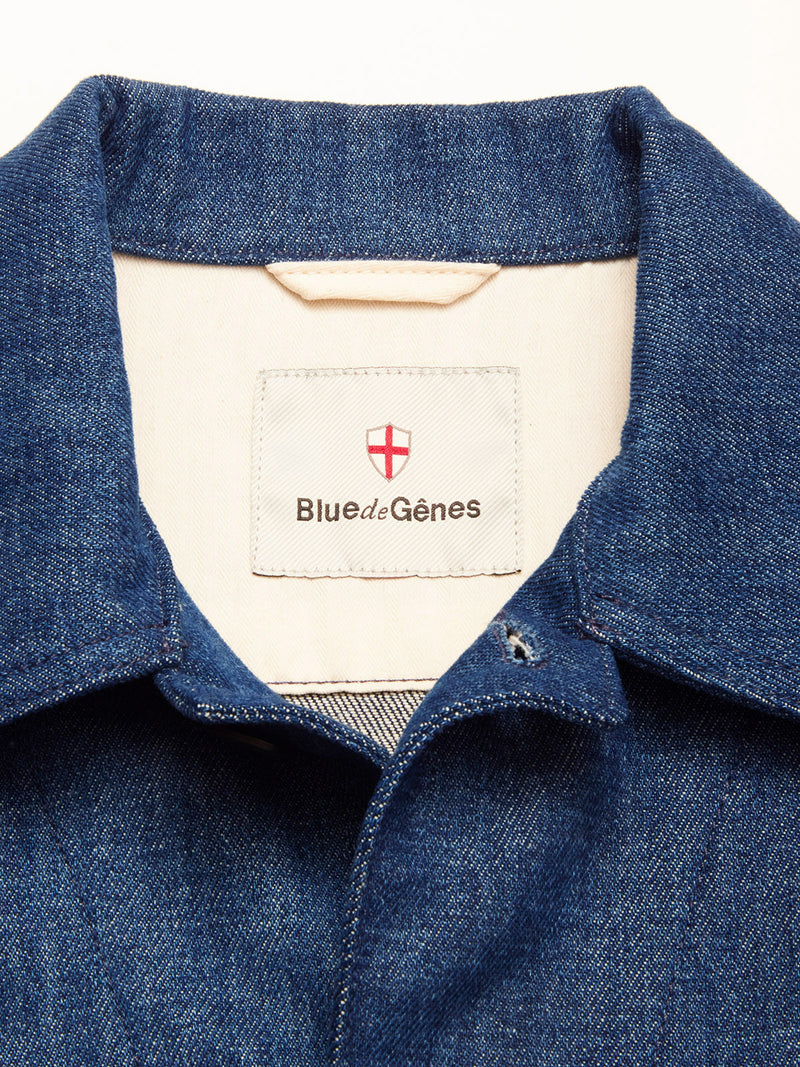 Close-up of the Yuma Fano Jacket - Denim Blue by Blue de Gênes, showing its workwear-inspired collar and an inner beige label with the Blue de Gênes name and a red and white shield logo above it.