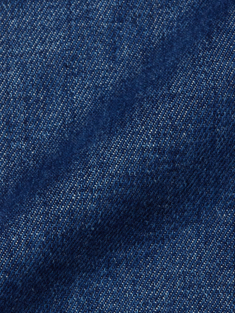 Close-up of the Yuma Fano Jacket - Denim Blue by Blue de Gênes, highlighting its heavy cotton blend denim fabric with detailed texture, weave pattern, subtle shading, and signature diagonal lines.