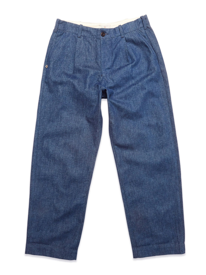 The Blue de Gênes Shogun Fano Pant in Denim Blue features a button and zipper closure, waist pleats, side pockets, and a relaxed straight-leg fit in heavy cotton blend, shown laid flat on a white background.