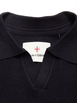 Close-up of the Blue de Gênes Otia L/S Polo Knit in navy, showing its ribbed texture, collar, and a white label with red shield emblem—an elegant detail in this luxury polo knit.