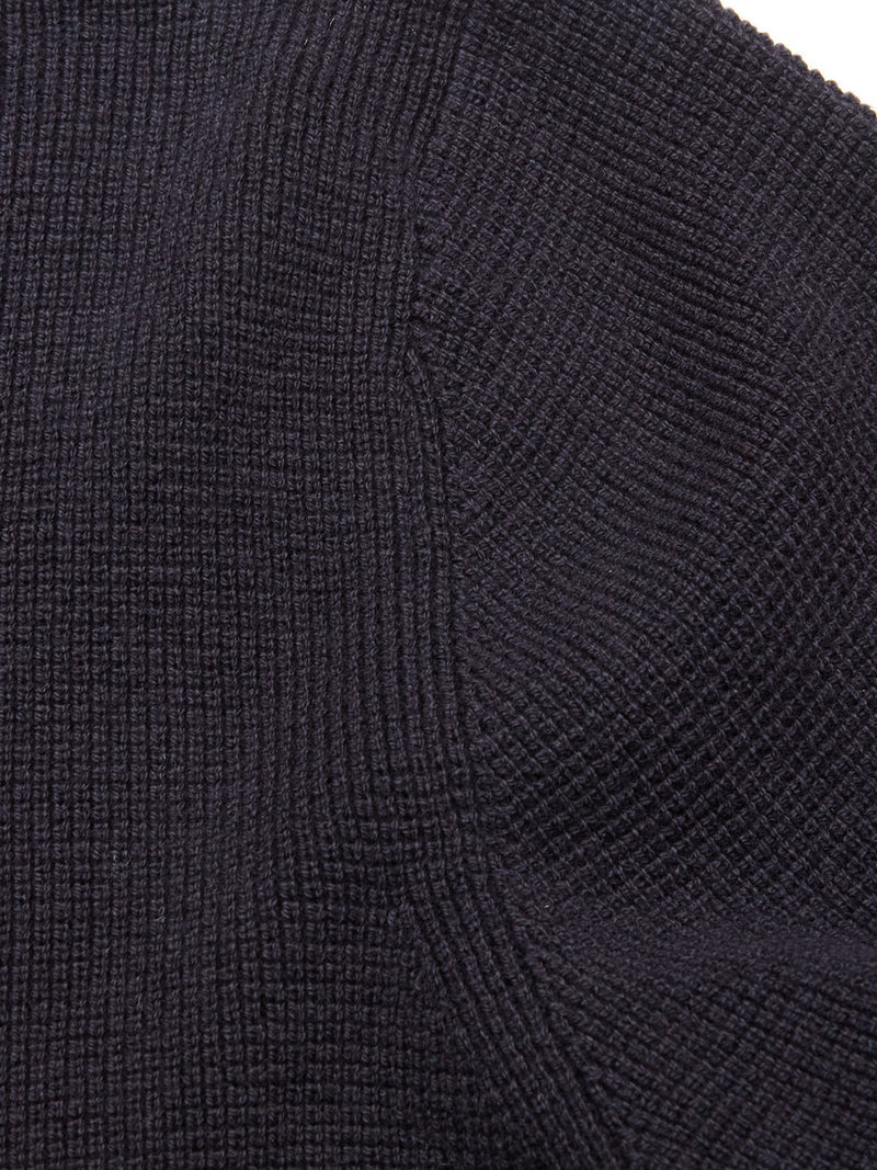 Close-up of a dark, textured fabric with a subtle grid pattern and visible seams, likely part of the Blue de Gênes Gifu Knit Cardigan in Navy.