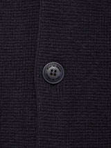 Close-up of the textured navy fabric and signature black four-hole button from the Blue de Gênes Gifu Knit Cardigan, highlighting its fine knit and quality craftsmanship near a neat vertical seam.