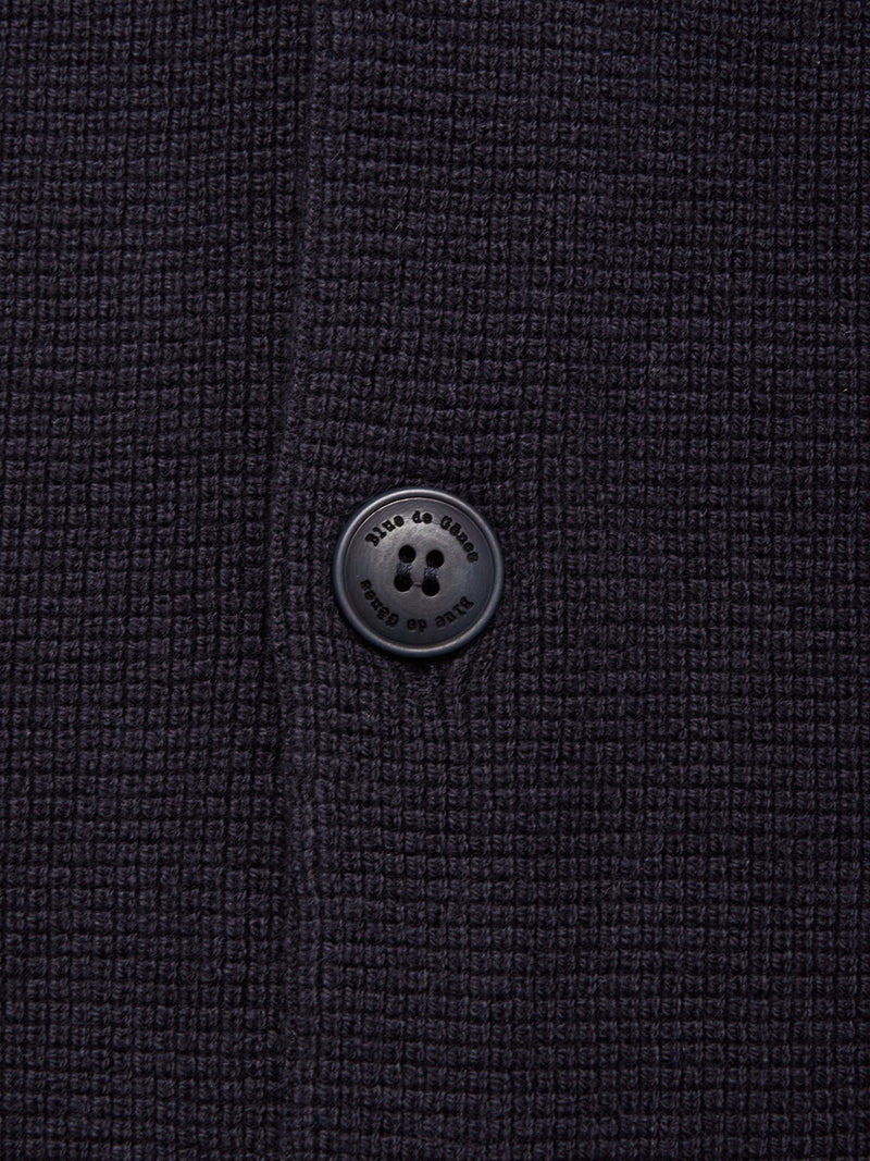 Close-up of the textured navy fabric and signature black four-hole button from the Blue de Gênes Gifu Knit Cardigan, highlighting its fine knit and quality craftsmanship near a neat vertical seam.