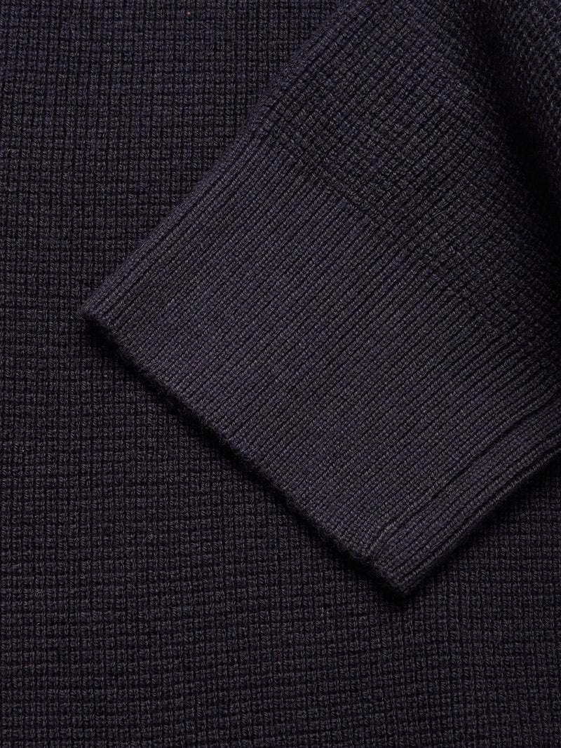 Close-up of the Blue de Gênes Gifu Knit Cardigan in navy, highlighting its fine ribbed and grid-like weave with a folded sleeve overlapping the main body.