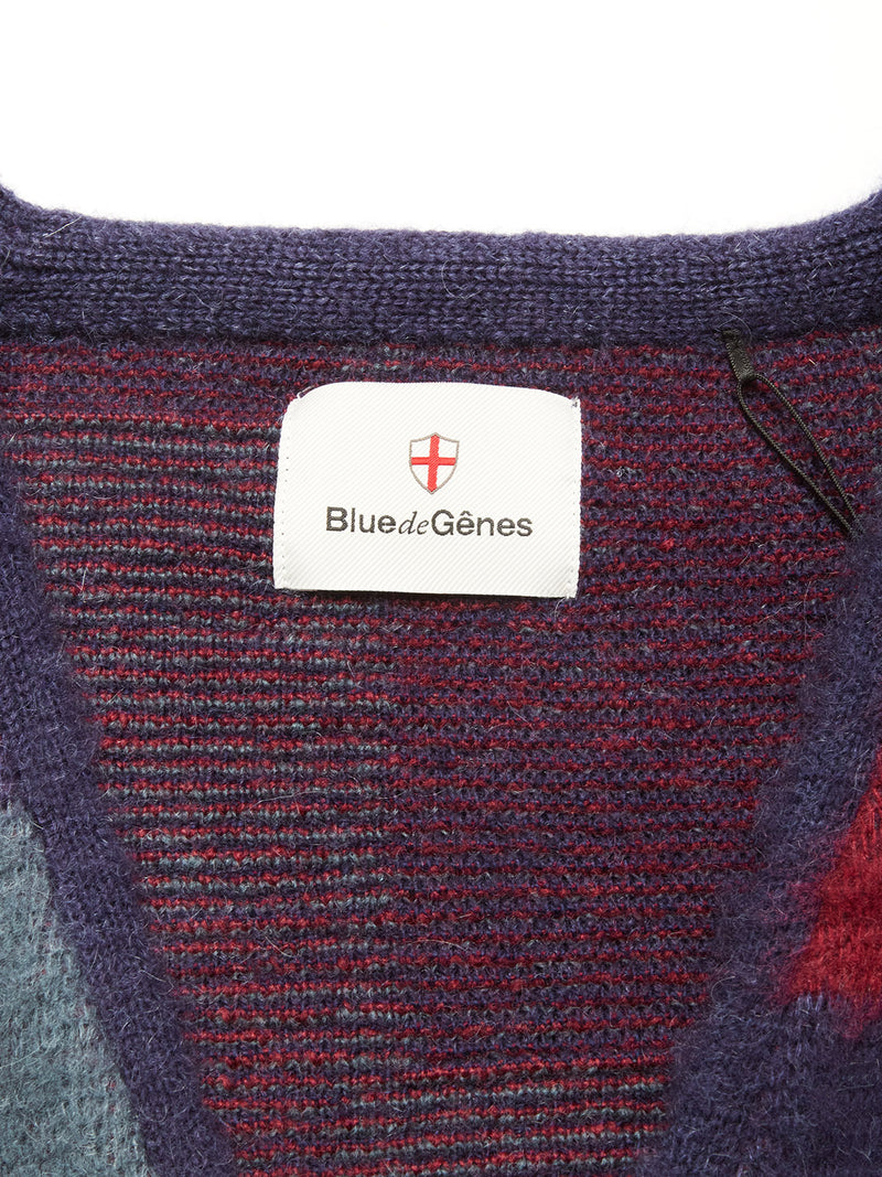 A close-up of a Blue de Gênes label with a red and white shield logo, sewn onto the textured Block Knit Cardigan - Navy Pattern.