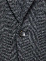 Close-up of the Blue de Gênes Fukui Blazer - Black Pattern, highlighting its refined herringbone fabric, a single black button with gold detail, and a defined notch lapel—a sophisticated spin on relaxed tailoring.