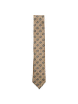 The Nekutaki Tie #E - Sand Pattern by Blue de Gênes features a tan weave with small dark circular designs, set on a sand pattern background—highlighting the brand’s timeless tailoring tradition.