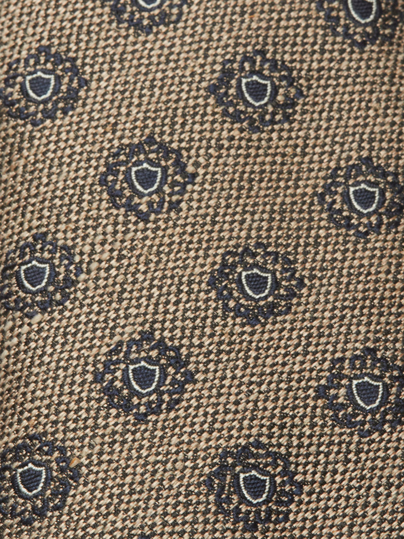 Close-up of the Nekutaki Tie #E - Sand Pattern by Blue de Gênes, showcasing textured brown fabric with a classic style and a repeating pattern of small dark blue and white floral circles.