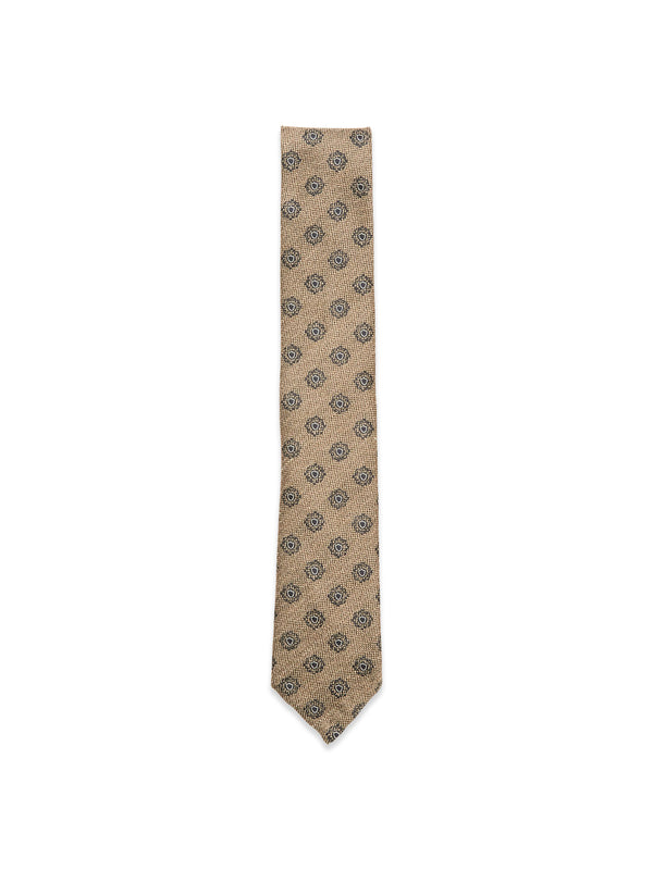 The Nekutaki Tie #E - Sand Pattern by Blue de Gênes features a tan weave with small dark circular designs, set on a sand pattern background—highlighting the brand’s timeless tailoring tradition.