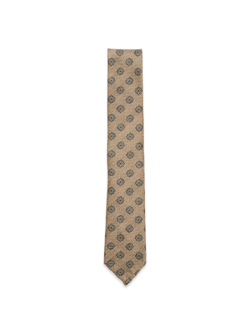 The Nekutaki Tie #E - Sand Pattern by Blue de Gênes features a tan weave with small dark circular designs, set on a sand pattern background—highlighting the brand’s timeless tailoring tradition.