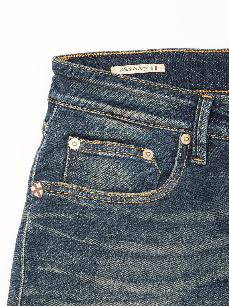 Close-up of Blue de Gênes Vinci Dark Vintage Jeans in mid blue denim, featuring five pockets, contrast stitching, metal rivets, and an inner Made in Italy label with Italian flag. Crafted from comfort stretch denim.