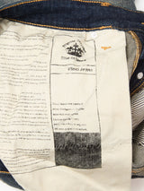 The inside pocket of Blue de Gênes Vinci Dark Vintage Jeans in mid blue denim displays the brand label, care instructions, and a denim story—all on cream-colored comfort stretch fabric with visible stitching.