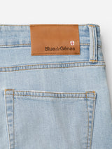 Close-up of the back pocket of BGvinci Trueblue Jeans in mid blue denim by Blue de Gênes, showing a brown leather patch above the pocket with the brand name and a small shield logo.