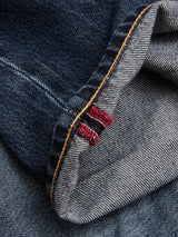 A close-up of cuffed BGmarco Rowan Jeans - Used by Blue de Gênes, featuring selvedge edges with red stitching, orange topstitching along the seam, and classic 5-pocket denim details.