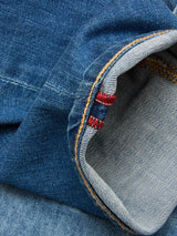 A close-up of Blue de Gênes BGrepi Misto Jeans - Med Used, featuring the cuff turned up to reveal the inner seam and distinctive red stitching along the edge.