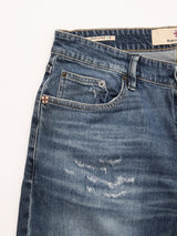 A close-up of Blue de Gênes BGvinci Striker Jeans - Dark Distress shows the front pocket, coin pocket, belt loops, rivets, distressed faded patches, and a "Made in Italy" label inside the waistband.