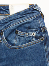 Close-up of BGrepi Kanto Jeans - Used by Blue de Gênes: blue denim slim-fit with front pockets, copper rivets, orange stitching, and a small white card partially tucked into the waistband. Durable design.