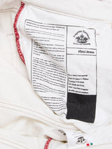 A close-up of the inside labels of BGvinci Bianco Jeans - White by Blue de Gênes, made in Italy, shows text about Leonardo da Vinci, care instructions, the brand logo, and red stitching on the waistband.