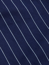 Close-up of navy blue fabric with evenly spaced, thin white diagonal pinstripes, reminiscent of classic workwear styles—featured in the Blue de Gênes BGpalco Toll Pants - Navy Stripe.