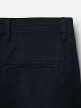 Close-up of the back pocket area of Blue de Gênes BGmenzo Vecchio Chino pants in dark navy, showing a single welt pocket and an embroidered shield-shaped logo above it.