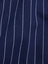 Close-up of the BGkendrick Toll Jacket - Navy Stripe by Blue de Gênes, featuring navy blue cotton fabric with fine white vertical pinstripes, visible texture, and detailed stitching that hint at its relaxed fit.