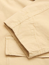 Close-up of the Blue de Gênes BGhunter Vecchio Jacket in Pale Khaki, highlighting beige cotton stretch fabric with visible stitching and a folded sleeve over the body.