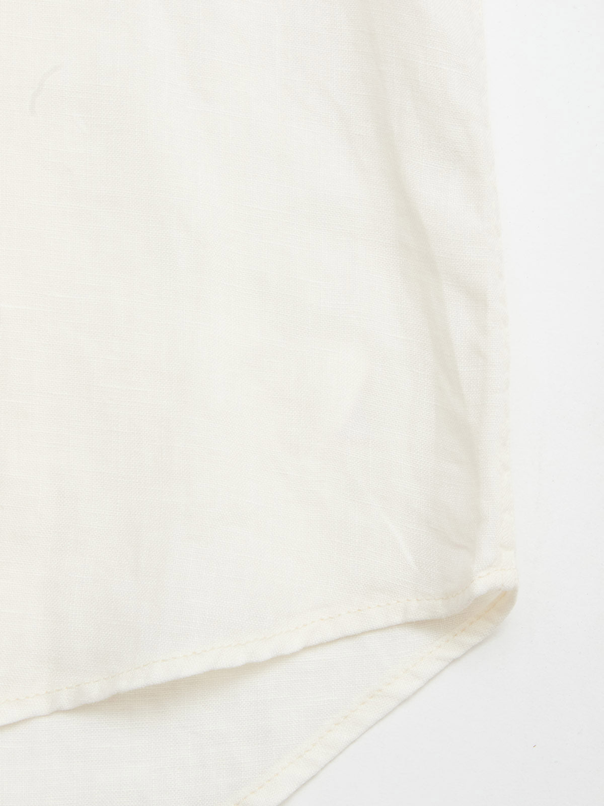 Close-up of the BGenric Hope L/S Shirt in Chalk by Blue de Gênes, showing fine stitching on soft, lightweight linen—ideal for summer. The shirt’s white fabric is displayed against a matching background.