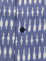 Close-up of the Blue de Gênes BGforma Onda S/S Shirt in blue with a white geometric cross pattern and a single dark blue button, offering an oversized fit perfect for a stylish resort look.