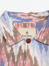 Close-up of the Blue de Gênes BGponti Kala S/S Shirt - Multi Pattern, made from 100% cotton with a blue, pink, and beige abstract print, tribal details, brown button, and label beneath a small shield emblem.