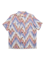 The Blue de Gênes BGponti Kala S/S Shirt features a multi-pattern tribal-inspired zigzag design in light blue, pink, brown, and white, with two chest pockets. Made from 100% cotton for comfort.