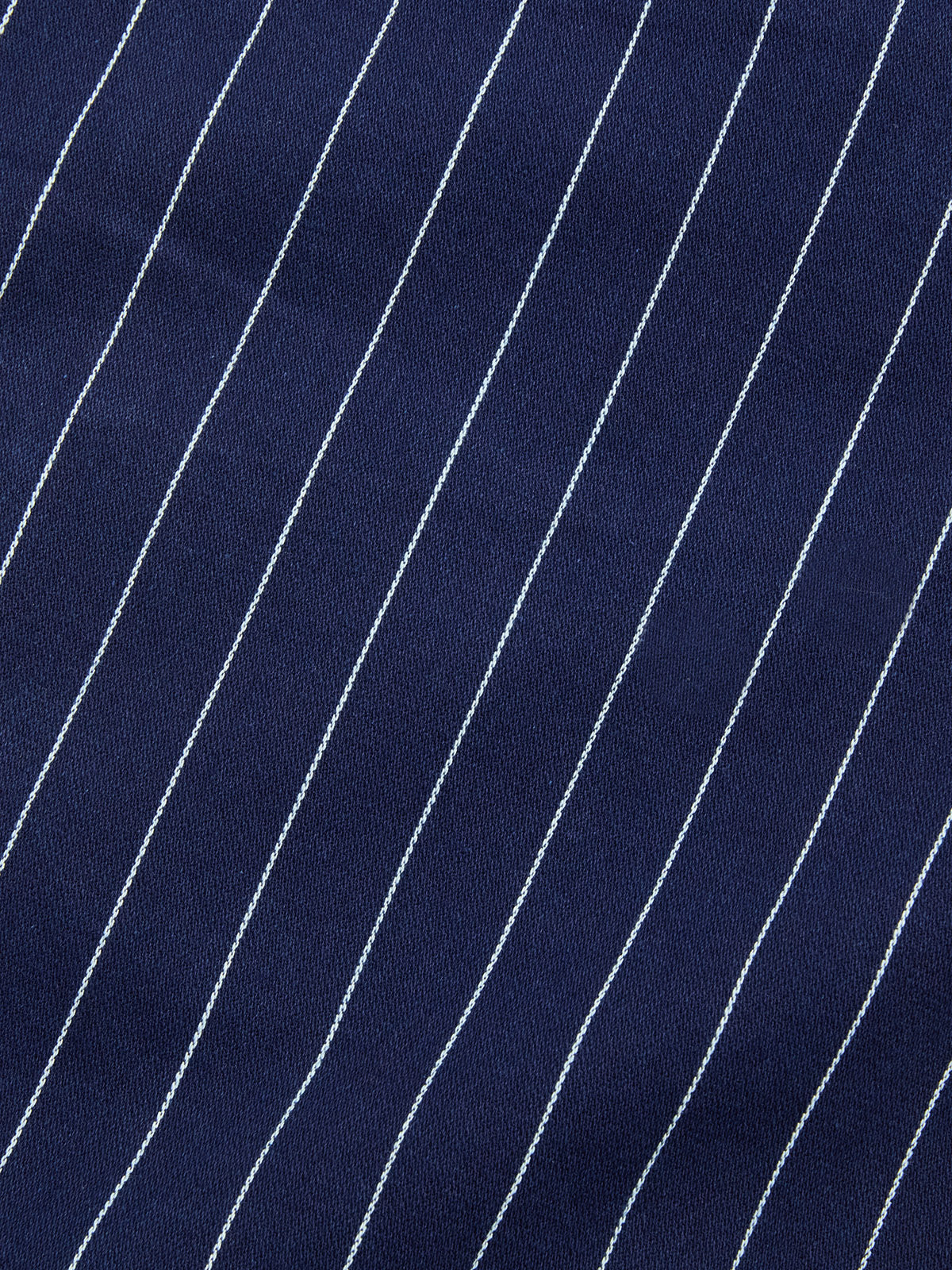 Close-up of BGcupra Toll Shorts - Navy Stripe by Blue de Gênes: dark blue fabric with evenly spaced white diagonal pinstripes, revealing a breathable texture ideal for summer workwear.