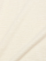 Close-up of BGmonty Knit - Chalk by Blue de Gênes: a light beige cotton linen blend fabric, showcasing its soft texture, subtle diagonal crease, visible weave, and gentle shadows.