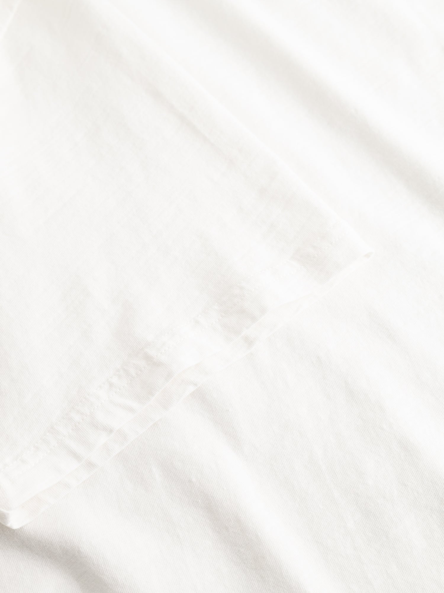 A close-up view of the BGoscar T-Shirt - Snow Fall by Blue de Gênes, crafted from smooth, soft 100% white cotton with gentle folds—ideal for a comfortable crewneck fit.