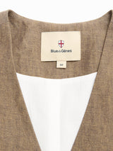 Close-up of a Blue de Gênes BGcanna Lin Gilet in Grey Mel, featuring a beige tag with a shield emblem inside the collar. Size “50” is below. The vest is lined with white fabric and showcases timeless style.